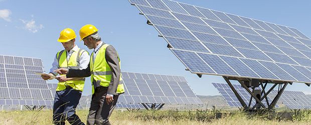 Trabajadores caminando junto a paneles solares en un paisaje rural